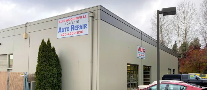 The corner of the Ali's Woodinville Auto Repair building, with a large Complete Auto Repair sign and the shop's phone number
